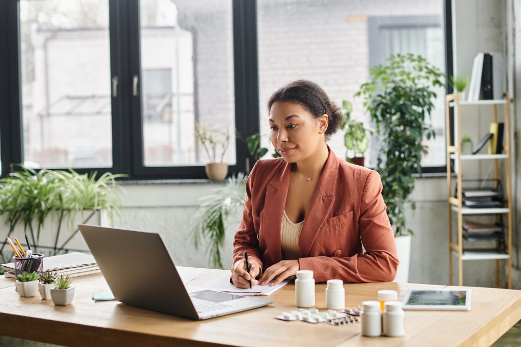 curly african american nutritionist taking notes for an online session in a modern workspace